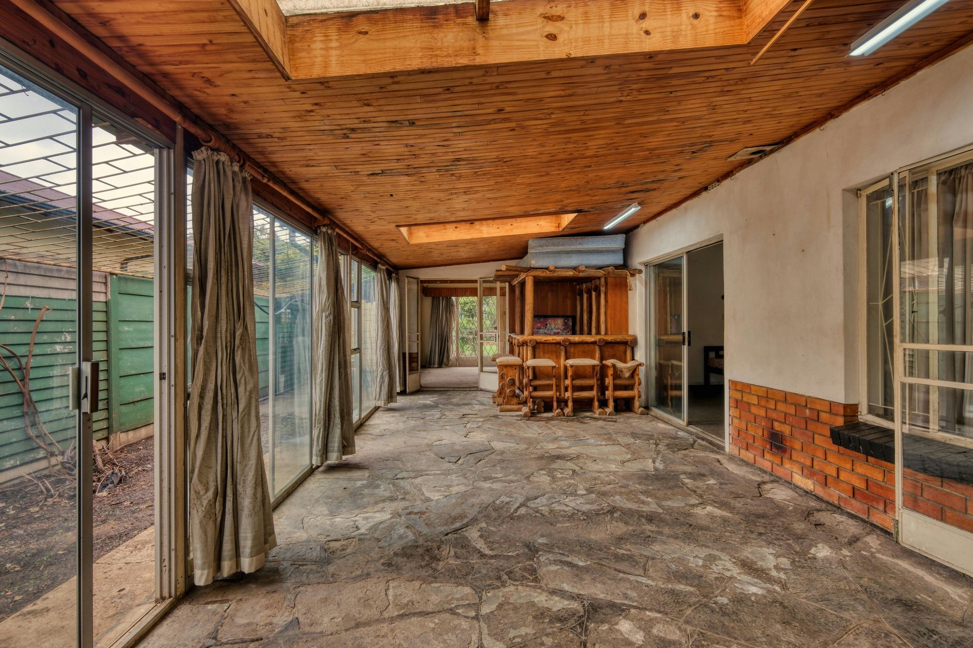 A raised timber sundeck with railings overlooking a back garden