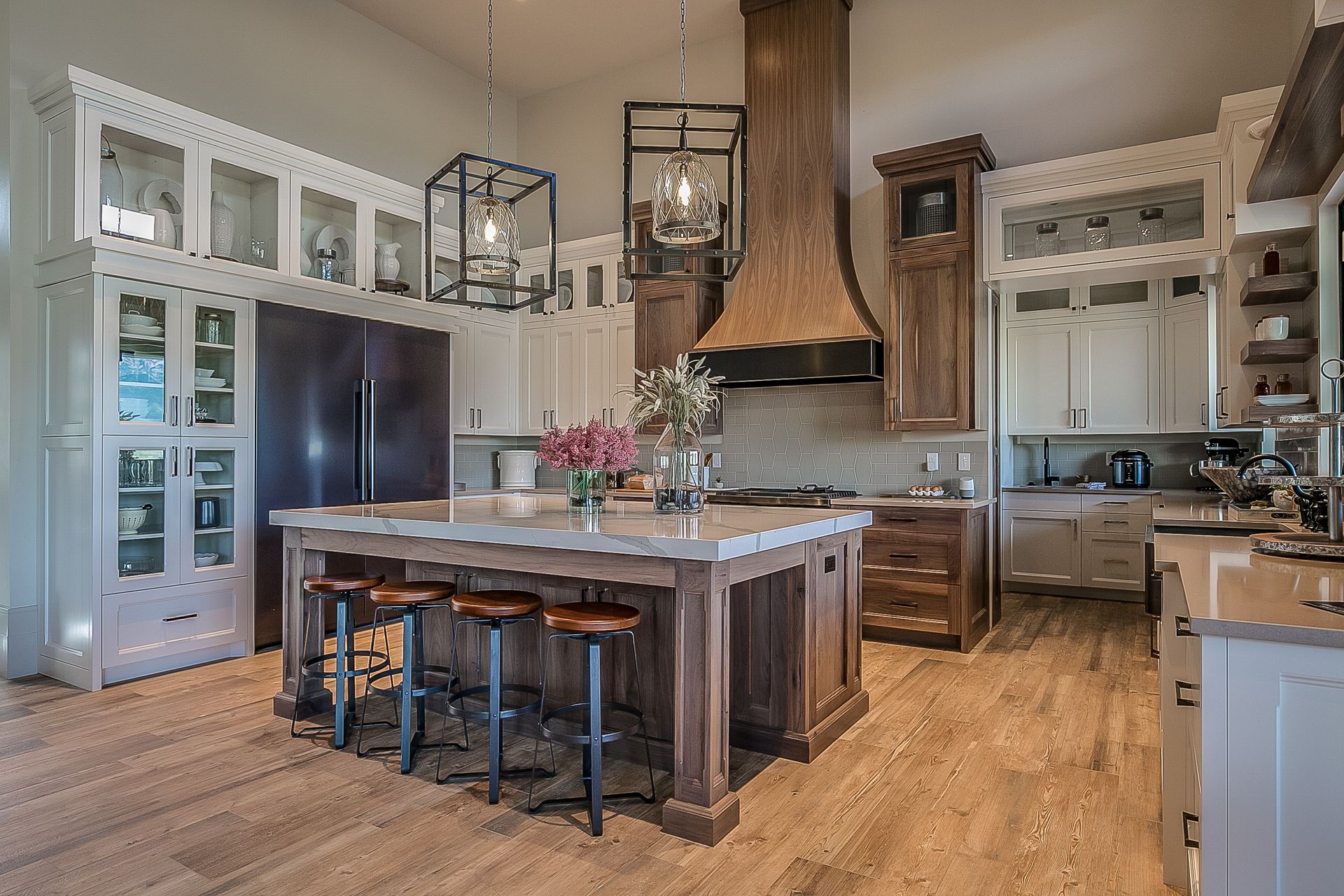 Renovated kitchen with a dark wood island, counter stools and glass-front cabinetry