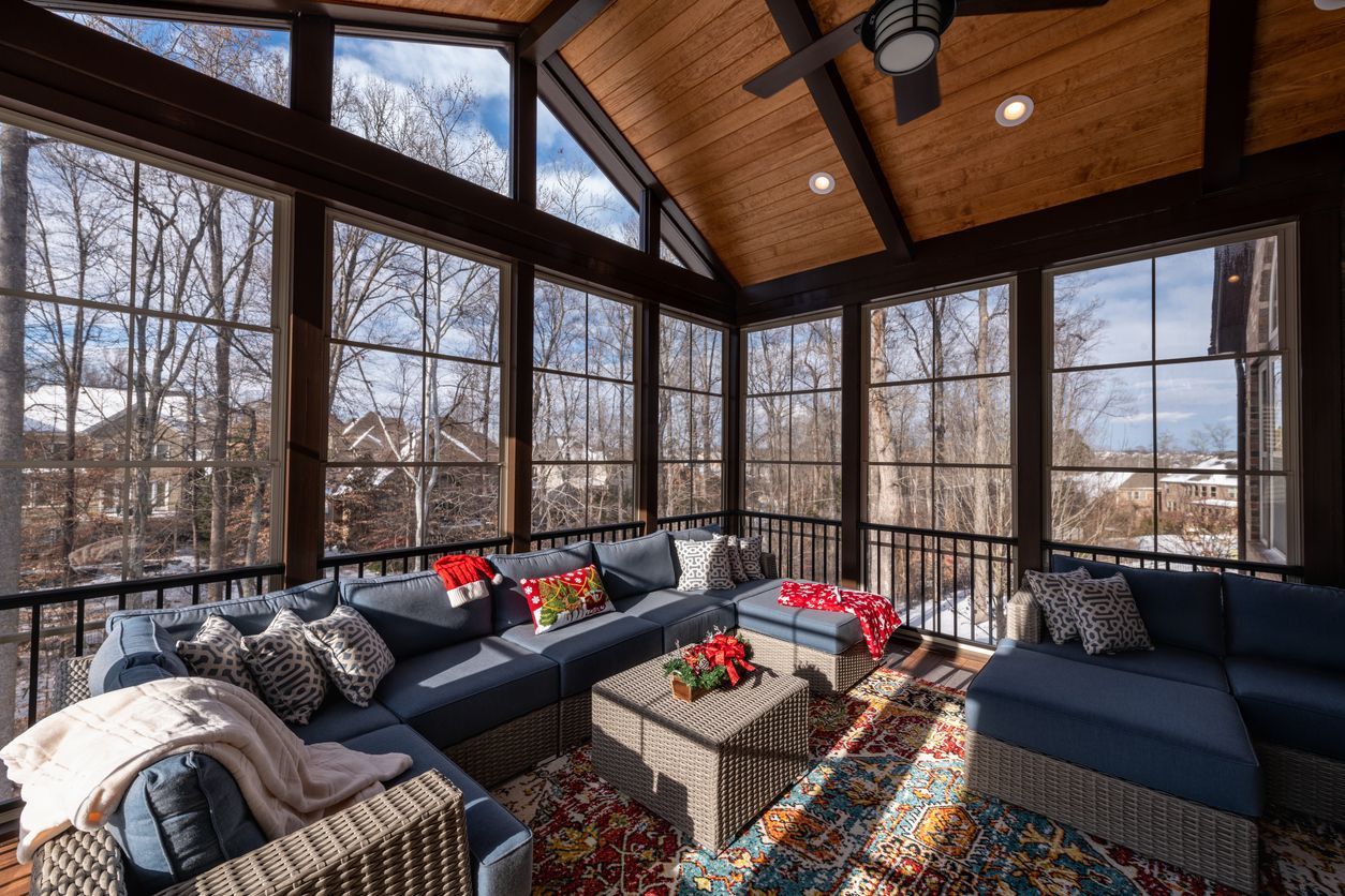 Screened sunroom with wicker seating, a patterned rug and an open view of the garden